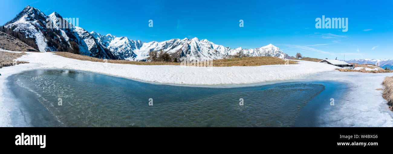 Panoramica della fusione del ghiaccio presso l'Alpe Piazza durante il disgelo di primavera e il Monte Legnone, Val Gerola, Valtellina, Lombardia, Italia Foto Stock