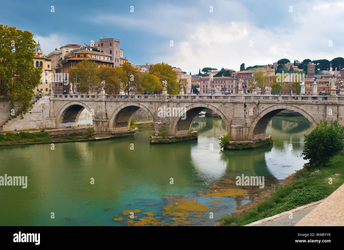 Immagine del rione Ponte distretto. Vista del bianco Ponte Sant'Angelo il ponte e la sua riflessione, alberi di arancio, verde acque del fiume Tevere sotto drammatico clo Foto Stock