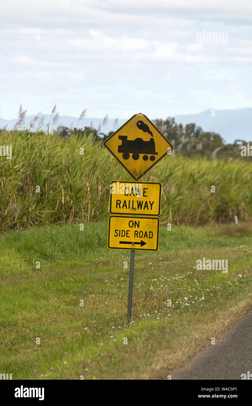 Un treno di zucchero attraversamento ferroviario segno accanto a una strada principale in campi di zucchero di canna nell'area di Mackay di Queensland in Australia. Mackay è il più grande p di zucchero Foto Stock