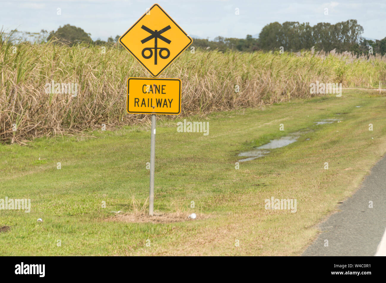 Un treno di zucchero attraversamento ferroviario segno accanto a una strada principale in campi di zucchero di canna nell'area di Mackay di Queensland in Australia. Mackay è il più grande p di zucchero Foto Stock