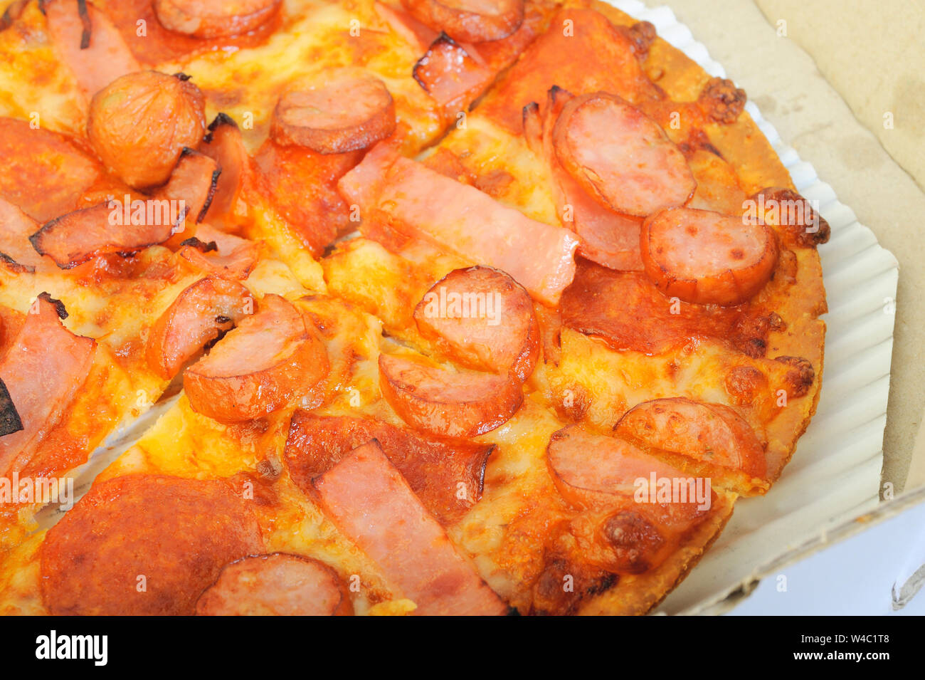 Pizza con mozzarella di bufala formaggi, prosciutto, salami, salsicce nella casella Foto Stock