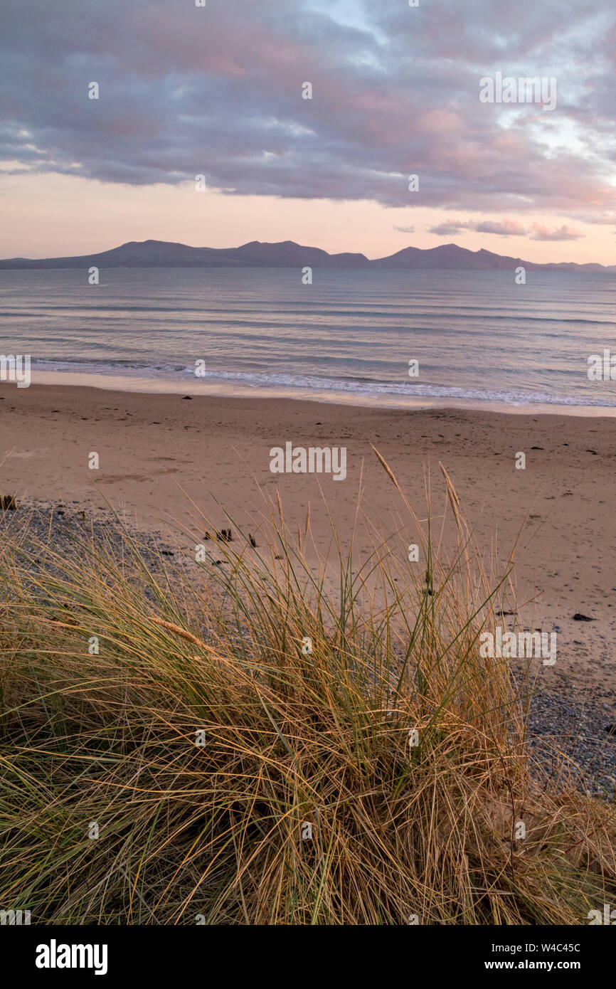 Tramonto sulla spiaggia di Newborough noto anche come Traeth Llanddwyn una lunga spiaggia sabbiosa di Anglesey cercando in tutta verso la penisola di Llŷn, Galles del Nord, Regno Unito Foto Stock