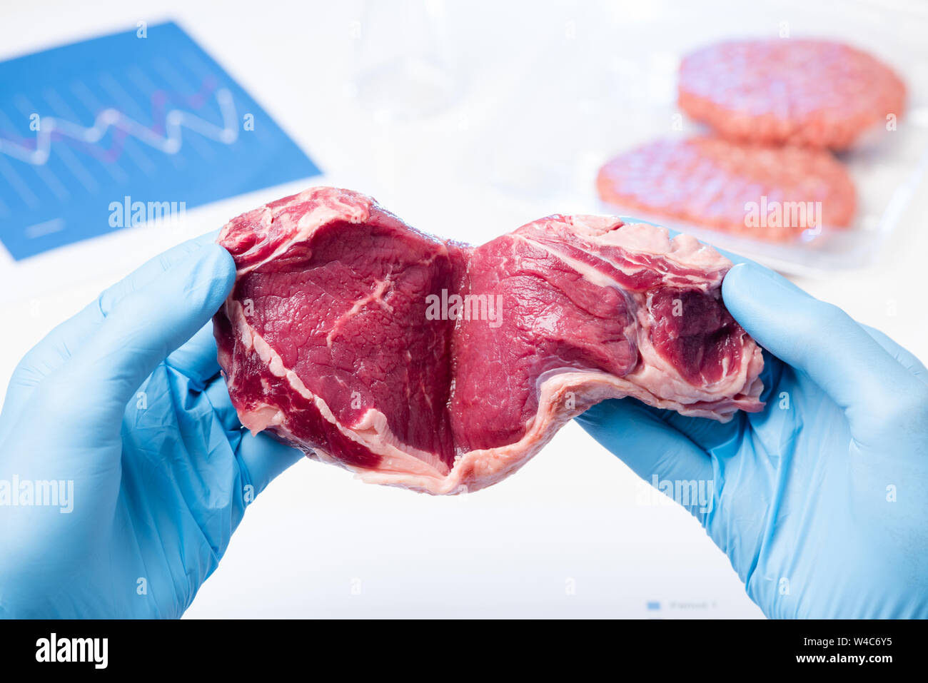 La carne rossa nel laboratorio scienziato mani. Ispezione delle carni controllo controllare o artificiale carne coltivate concetto. Foto Stock