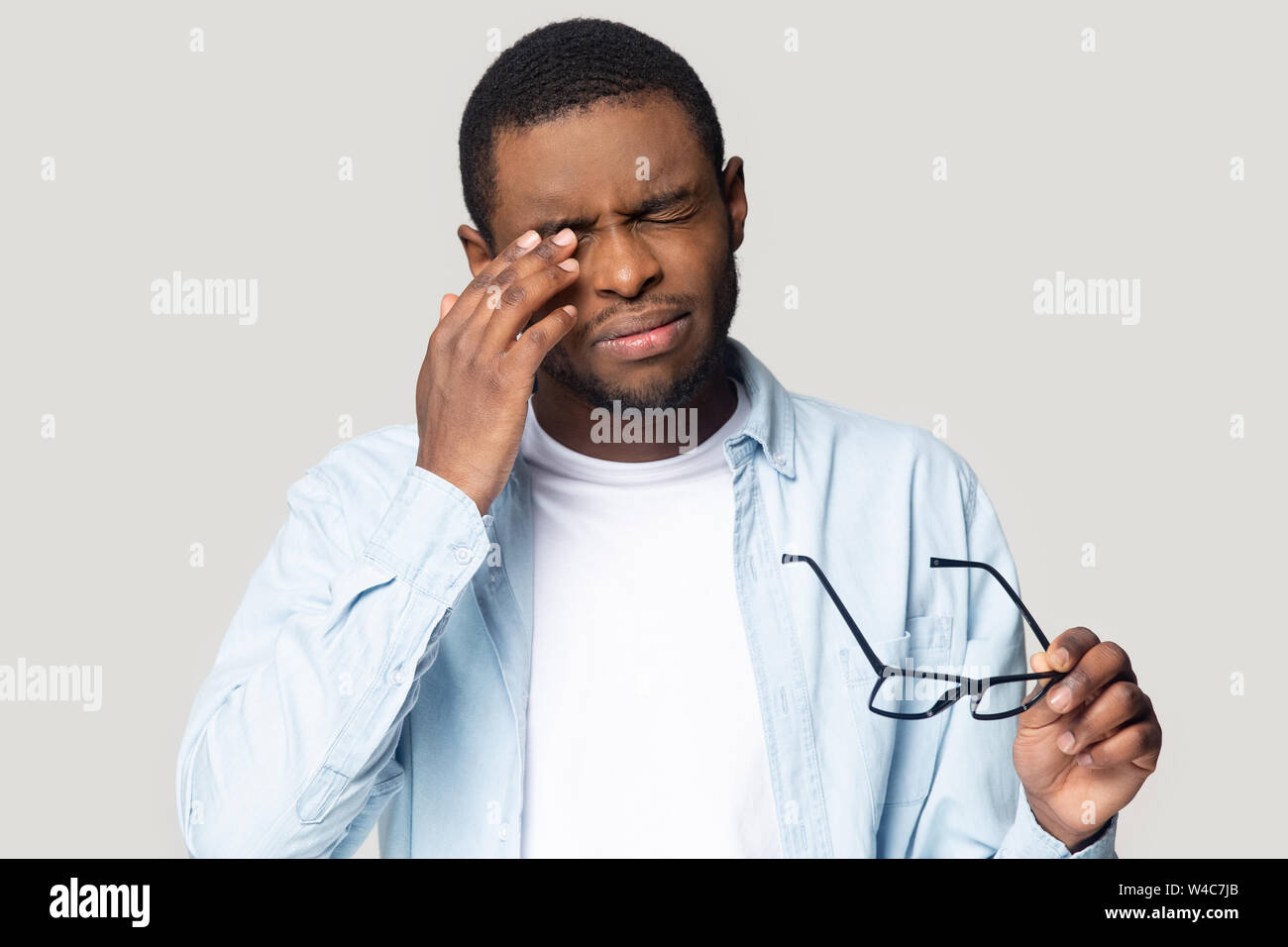 African American maschio di togliere i bicchieri che soffrono di mal di testa Foto Stock
