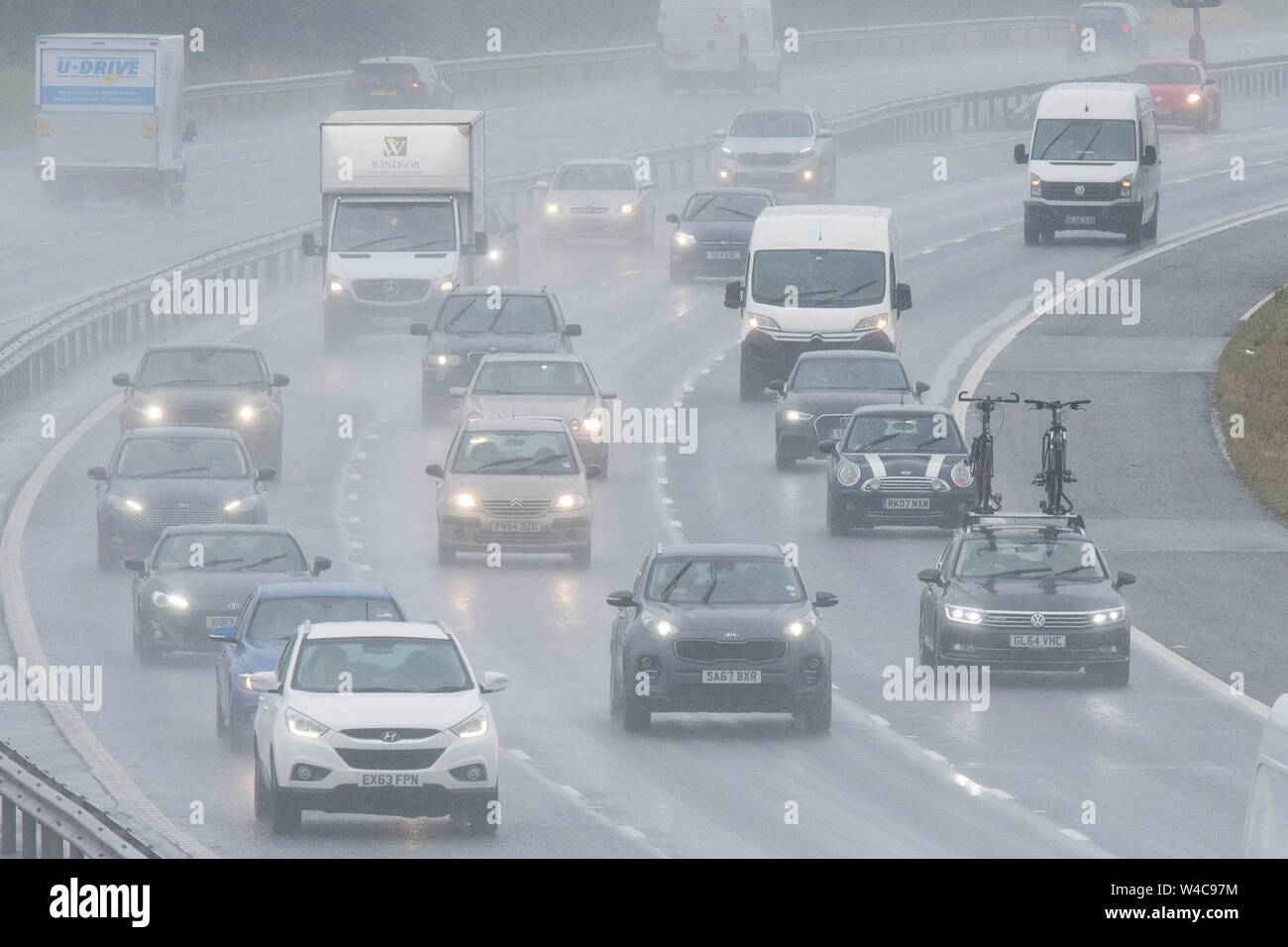 Veicoli viaggiano lungo M40 autostrada nr Warwick attraverso la pioggia e il traffico pesante come il popolo colpito la strada per le vacanze estive. Il 19 luglio 2019. Foto Stock