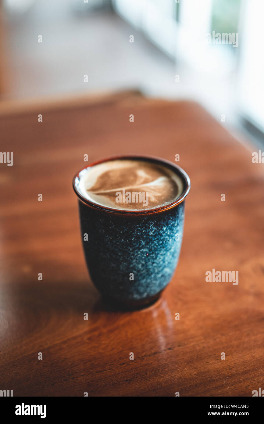 In casa il caffè in un blu coppa in ceramica su un tavolo di legno. Foto Stock
