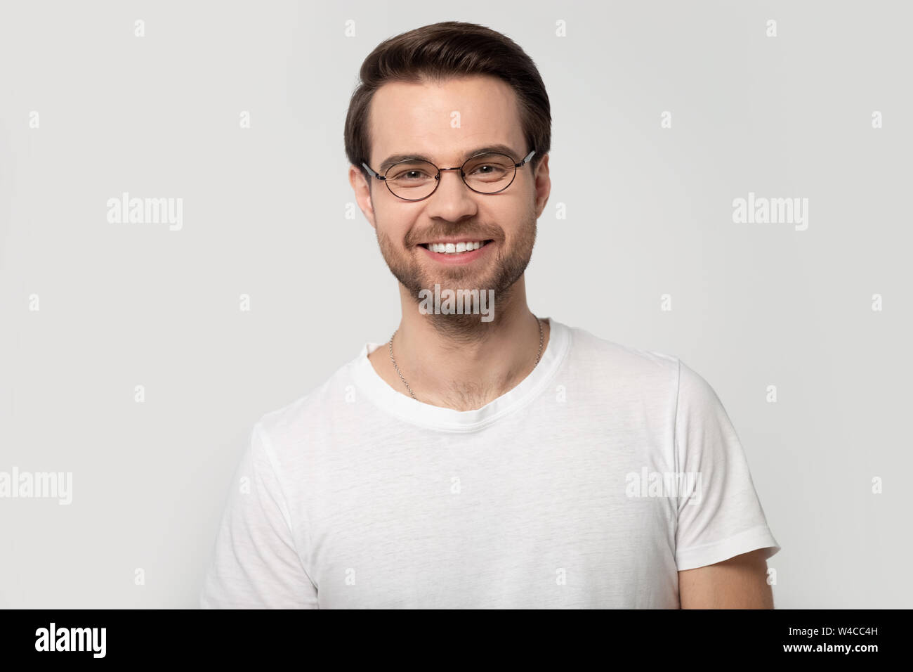 Headshot ritratto uomo sorridente con gli occhiali isolato su sfondo grigio Foto Stock