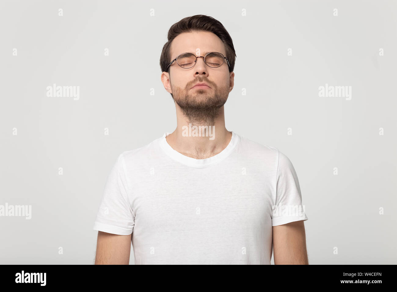 Giovane uomo occhi chiusi sognando isolato su grigio di sfondo per studio Foto Stock