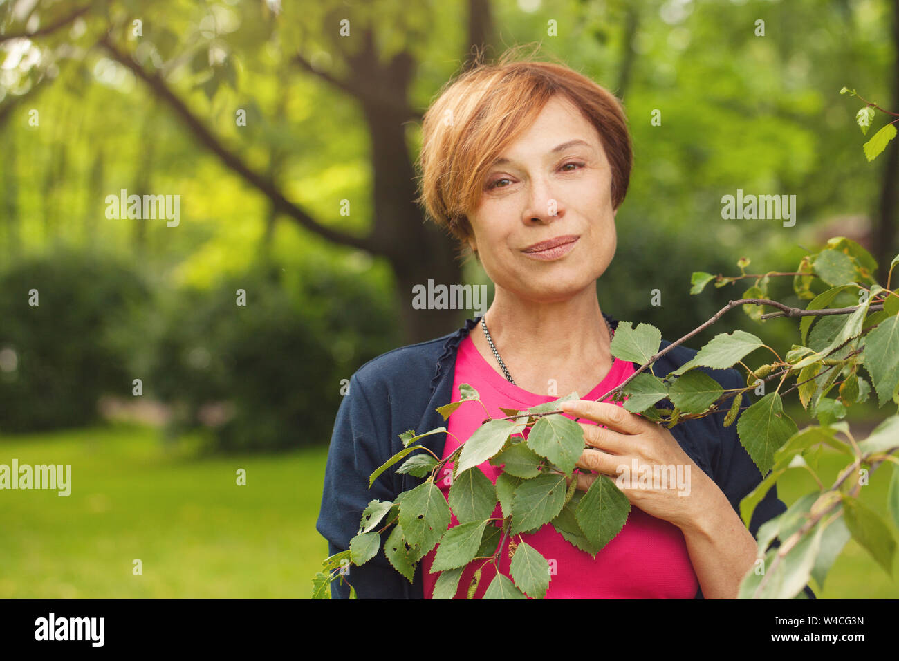 Bella donna anziana con foglie di colore verde all'aperto. Bella coppia modello 60 anni Foto Stock
