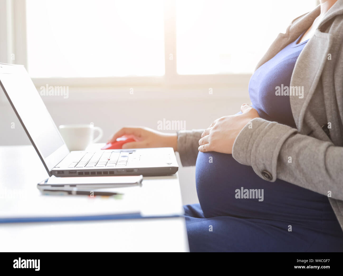 donna incinta sta lavorando su computer portatile e telefono cellulare, business Foto Stock