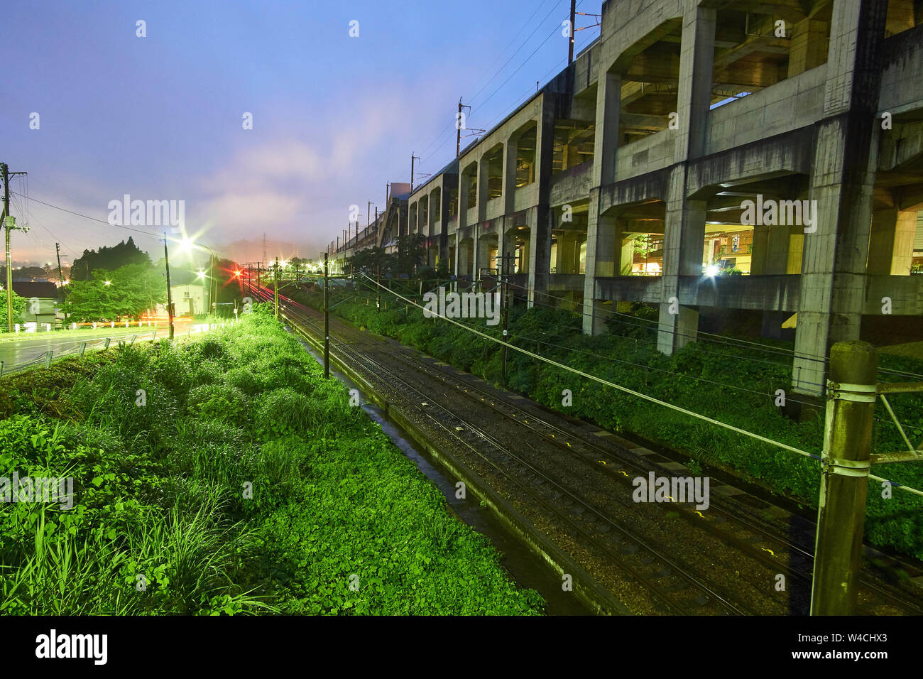 La linea Joetsu corre parallela al sollevato le vie del Joetsu Shinkansen bullet train line su una serata di nebbia in Yuzawa, Giappone. Foto Stock