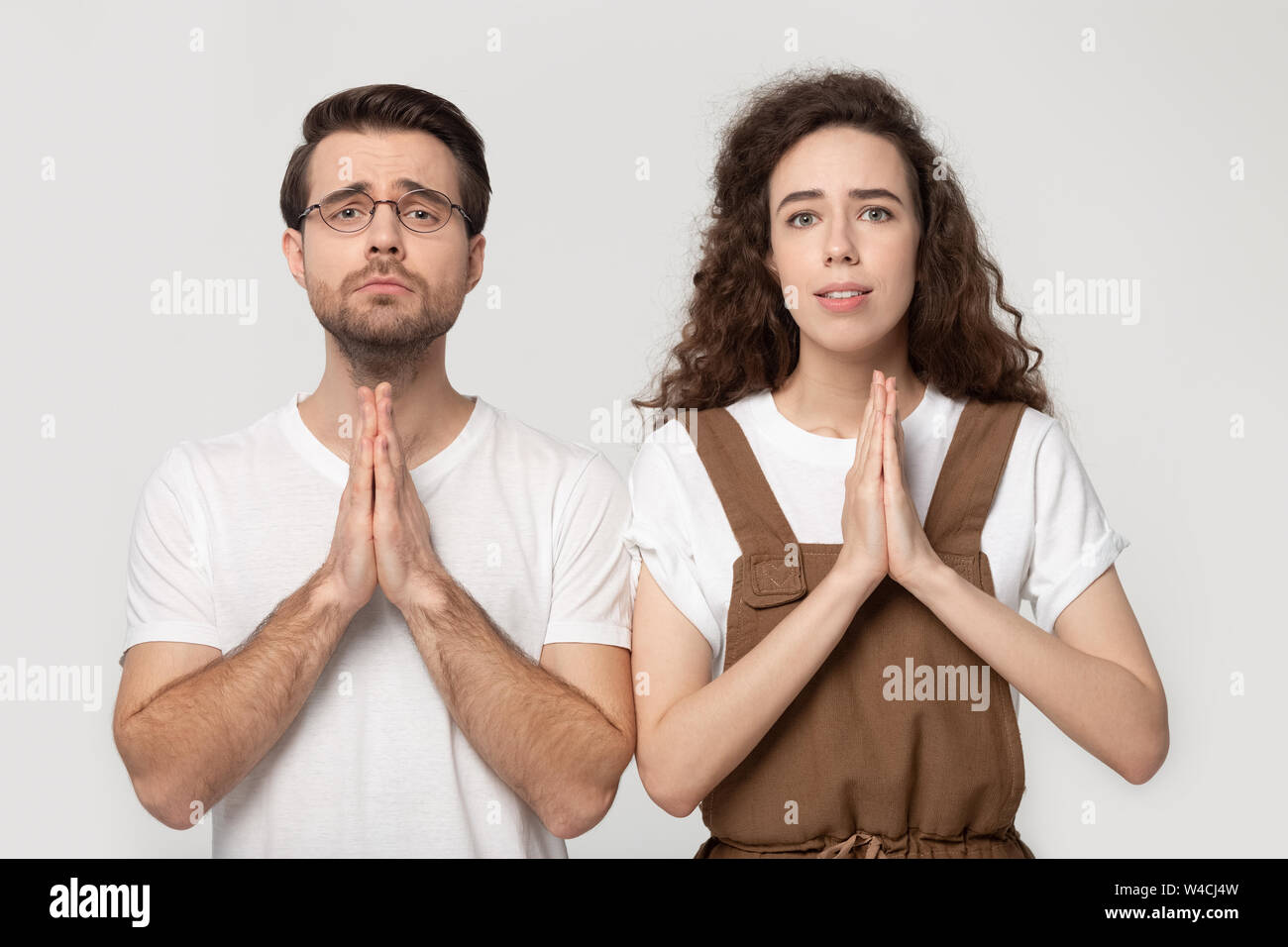 Accoppiare la piegatura mani insieme pregando in posa isolato su sfondo grigio Foto Stock