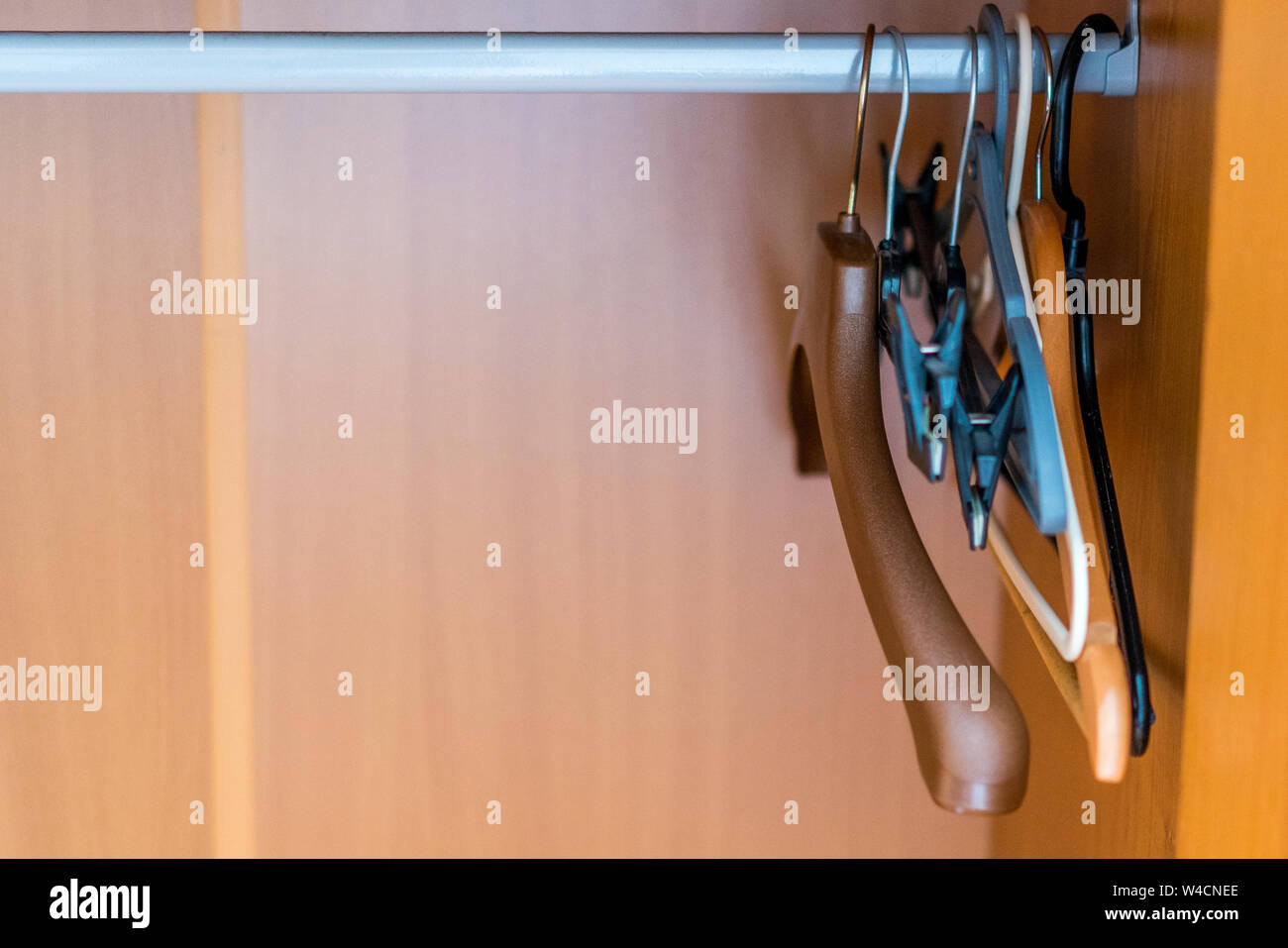 Primo piano di diverse grucce appendiabiti in un vuoto di armadio in legno Foto Stock