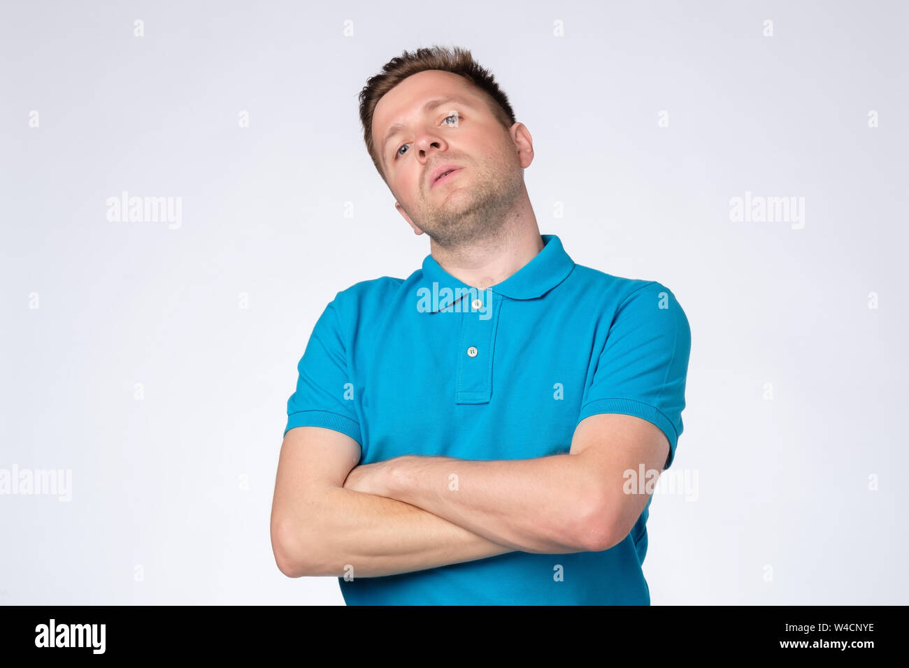 Uomo in posa di studio con le braccia incrociate e fissando la telecamera con arrogante presuntuoso cercare Foto Stock