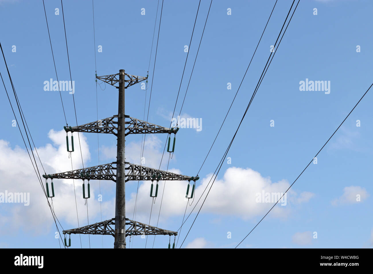 Tensione alta torre con fili elettrici sul cielo blu e nuvole bianche sfondo. Linee di trasmissione di energia elettrica, alimentazione concept Foto Stock