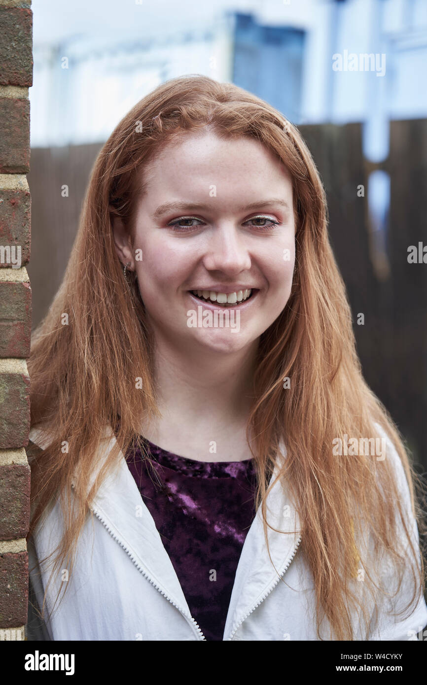 Ritratto di sorridente ragazza adolescente appoggiata contro la parete nel contesto urbano Foto Stock
