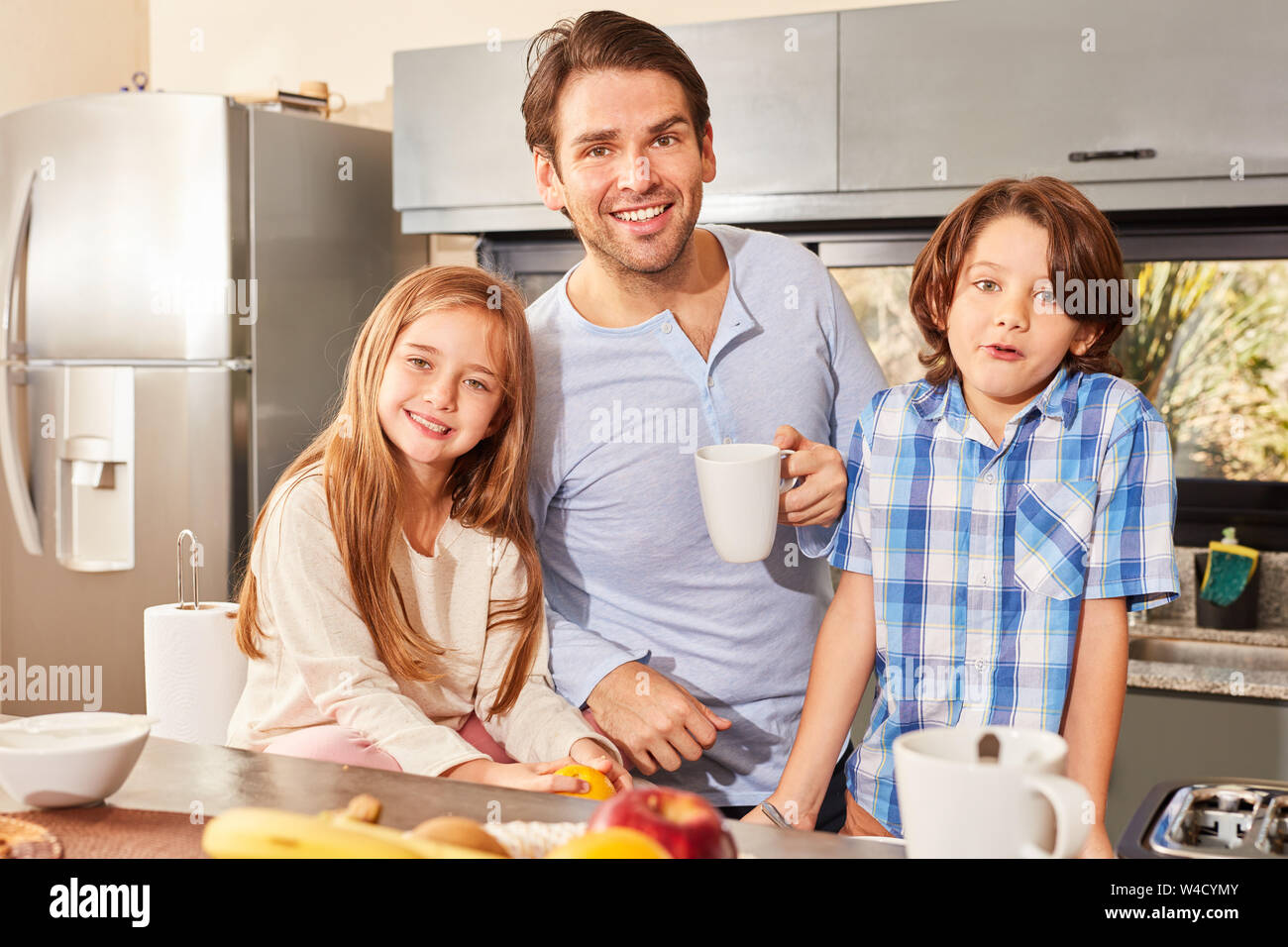 Unico padre e due bambini di avere la prima colazione al mattino in cucina Foto Stock