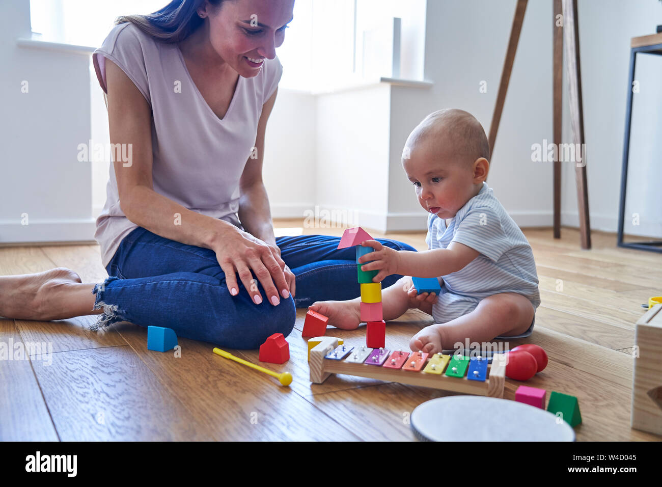 Madre con 8 mese vecchio Figlio bambino imparare giocando con i colori dei blocchi di legno a casa Foto Stock