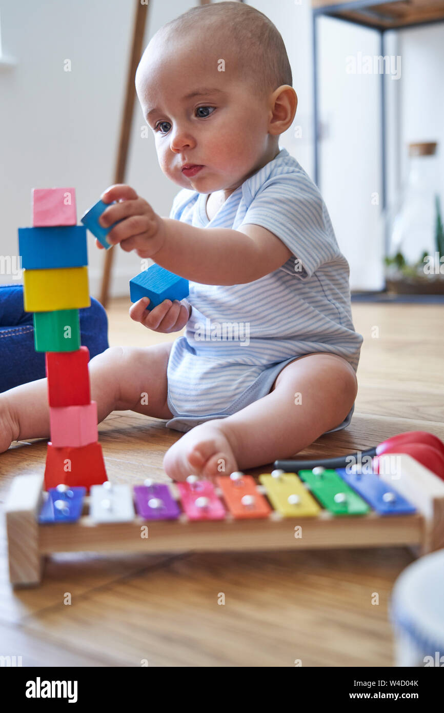 Madre con 8 mese Baby figlio imparare giocando con i colori dei blocchi di legno a casa Foto Stock