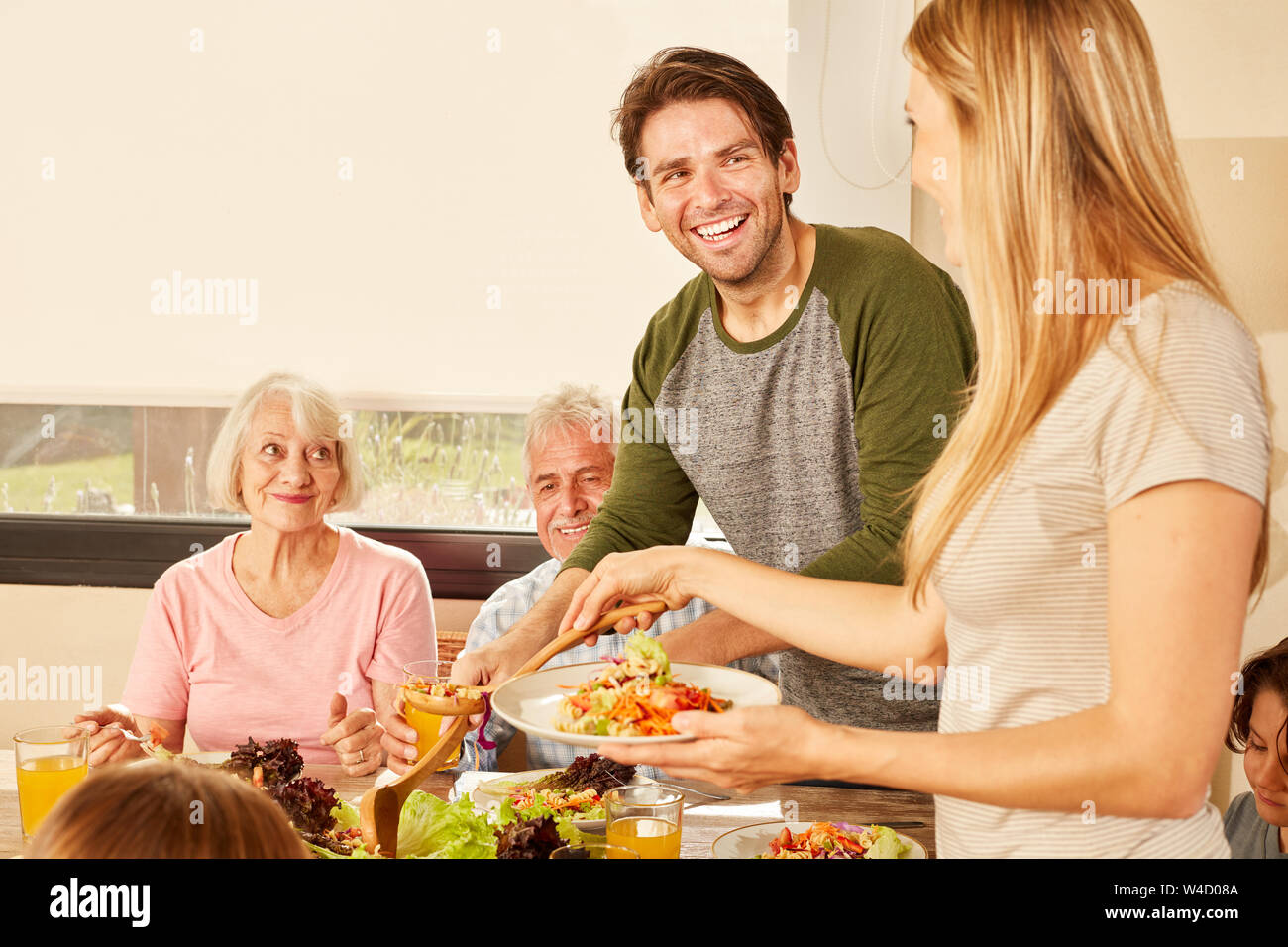 Coppia felice con i nonni al tavolo da pranzo a pranzo o cena Foto Stock