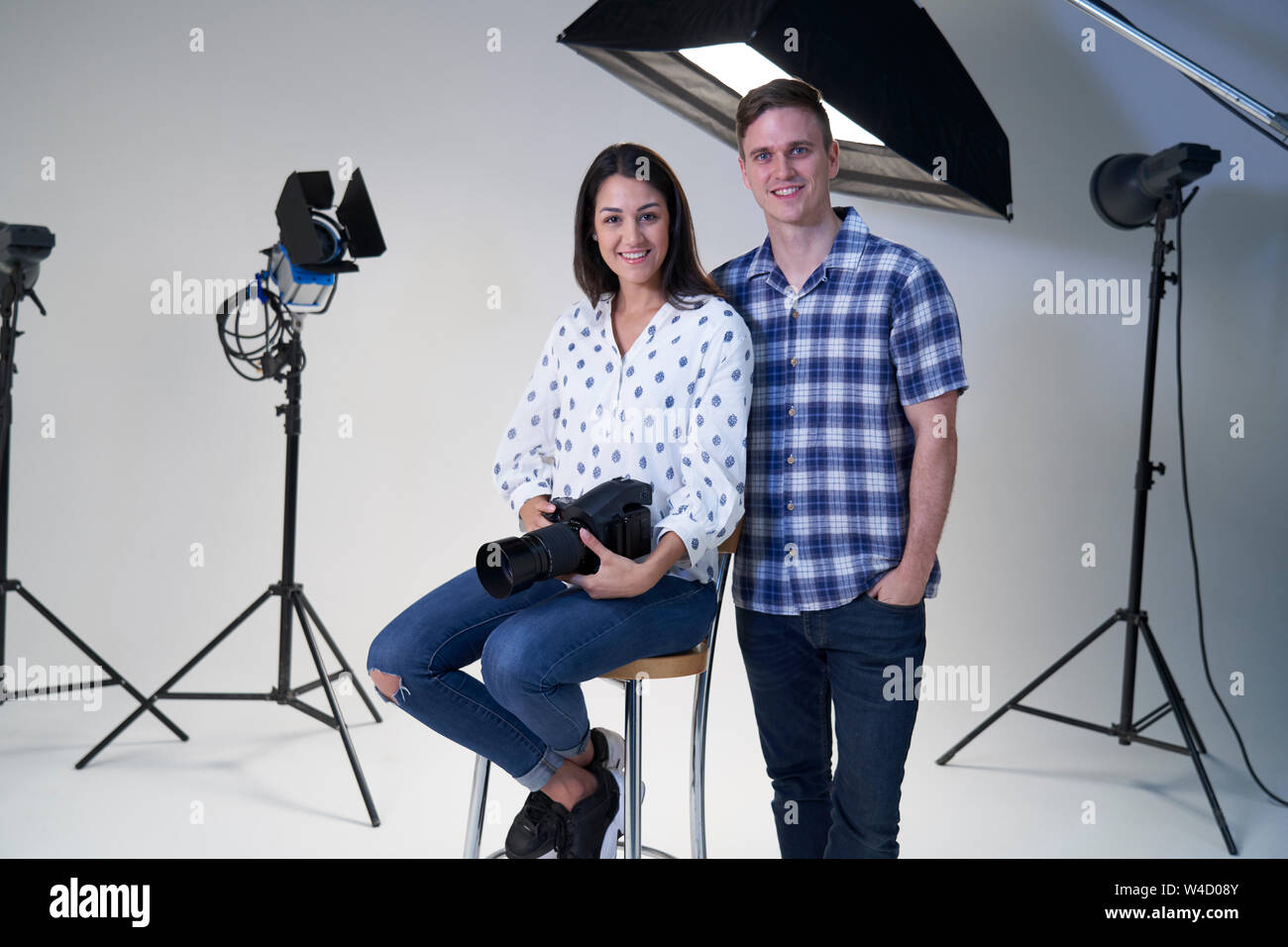 Ritratto di maschi e femmine di fotografi in studio per scattare foto con la fotocamera e apparecchiature di illuminazione Foto Stock