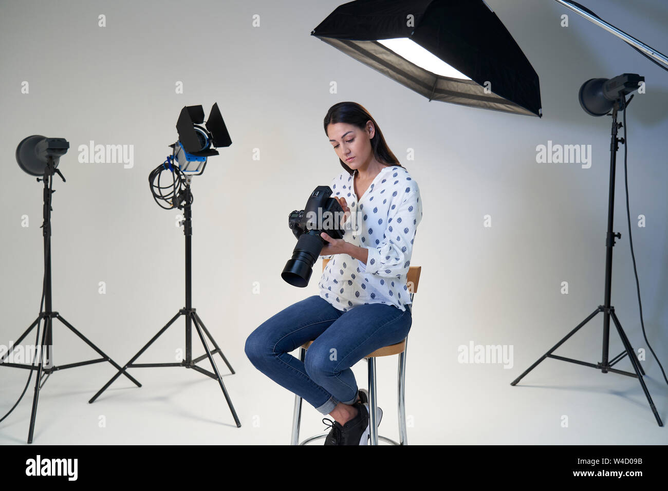 Fotografo femmina in studio per scattare foto con la fotocamera e apparecchiature di illuminazione Foto Stock