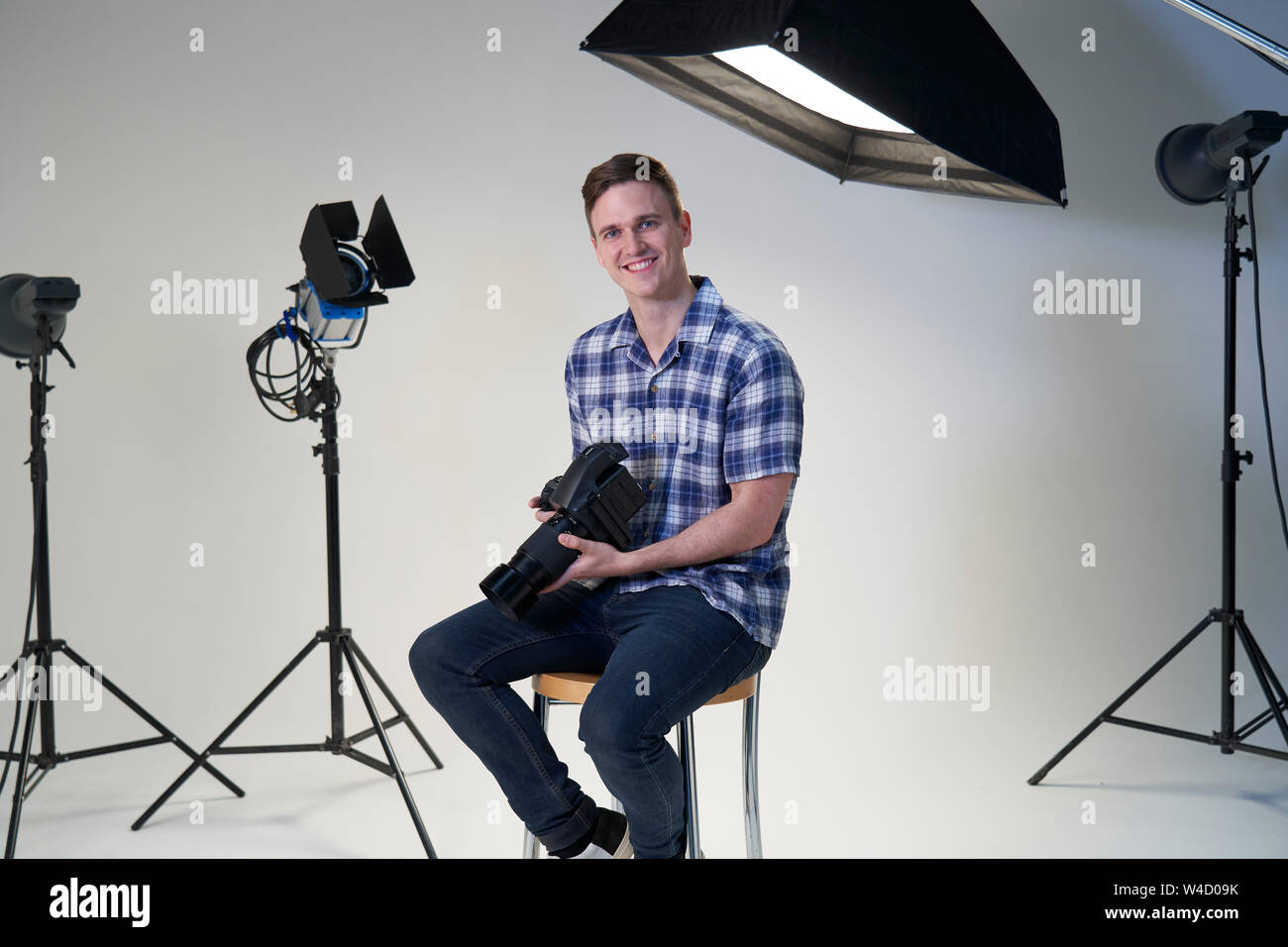 Ritratto di fotografo maschio in studio per scattare foto con la fotocamera e apparecchiature di illuminazione Foto Stock