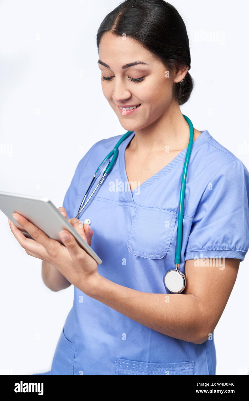 Studio shot di infermiera femmina indossando Scrubs utilizzando tavoletta digitale Foto Stock