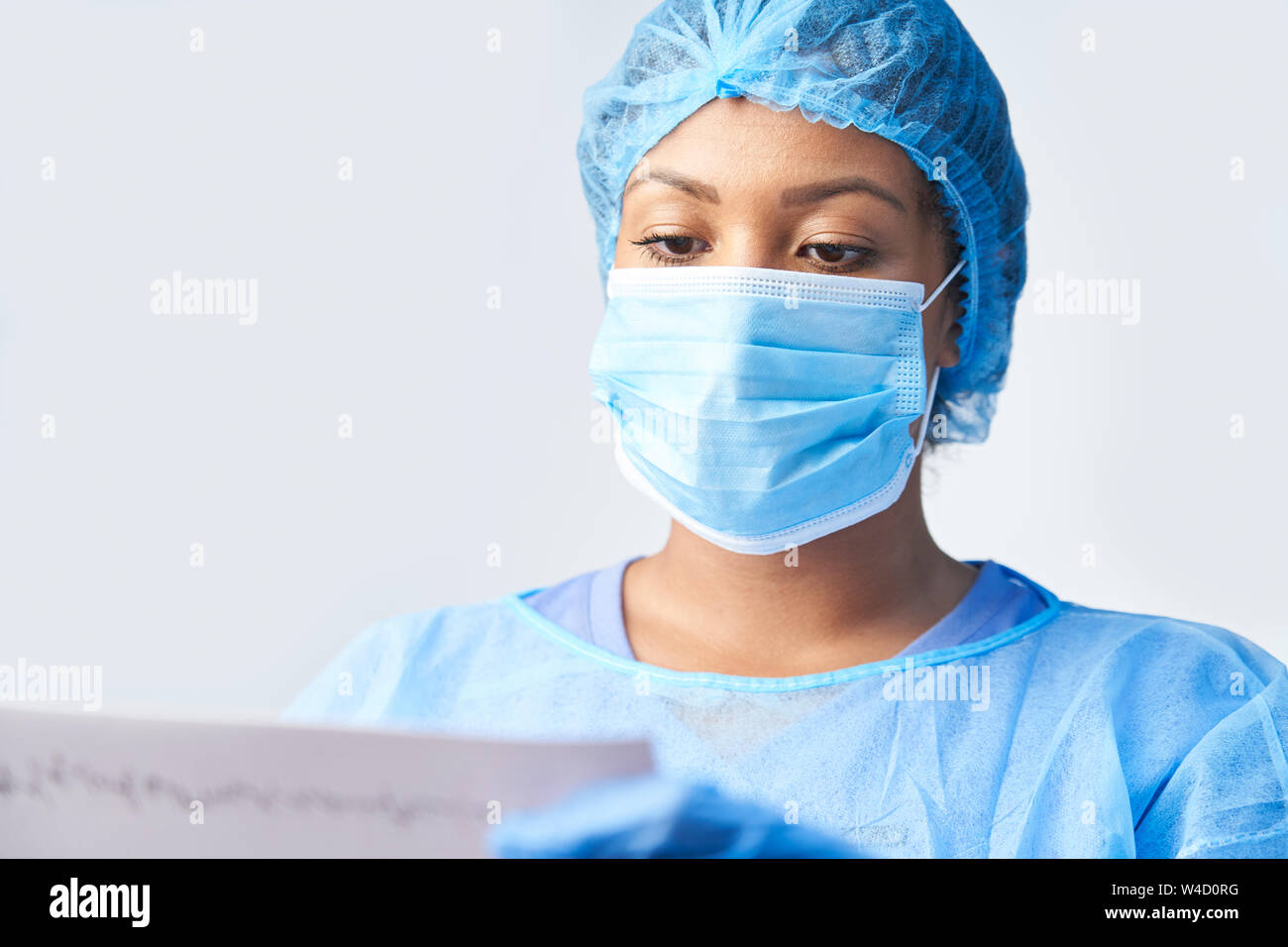 Studio shot del chirurgo femmina indossando camice e maschera Holding Medical Stampare Foto Stock