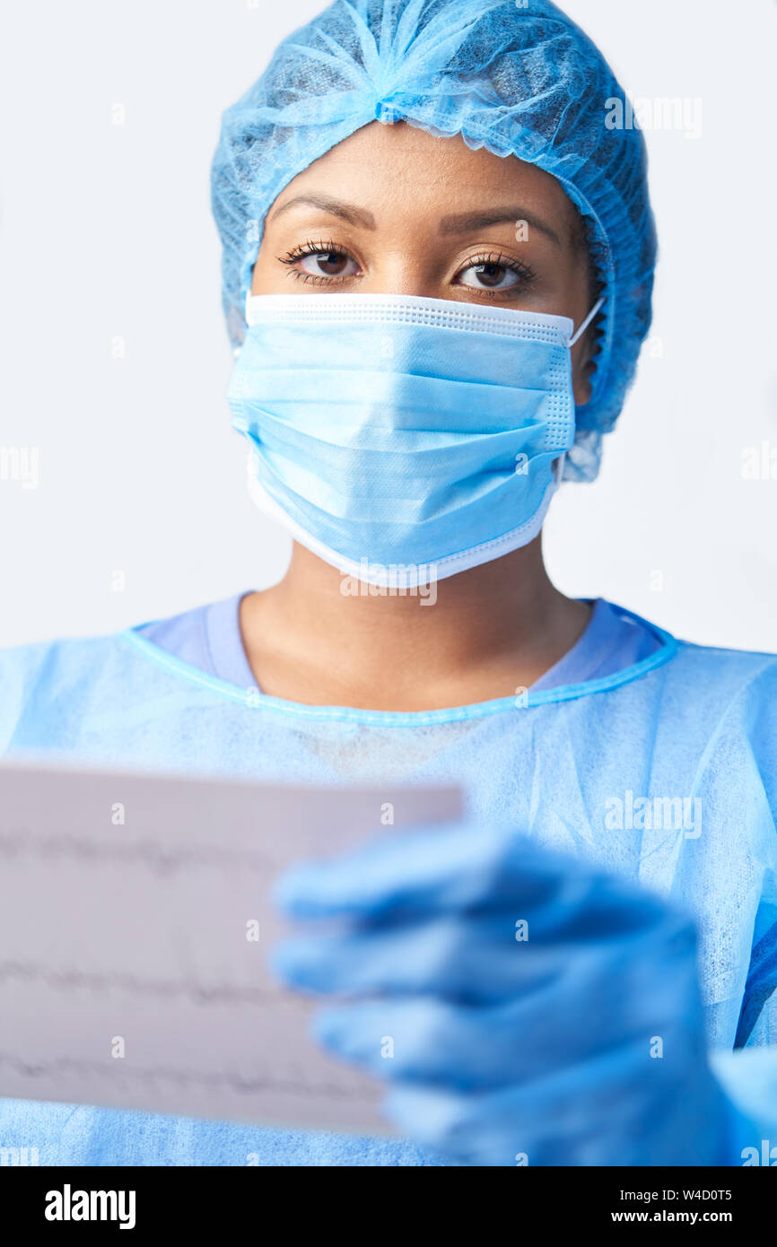 Studio ritratto di donna chirurgo indossando camice e maschera Holding Medical Stampare Foto Stock