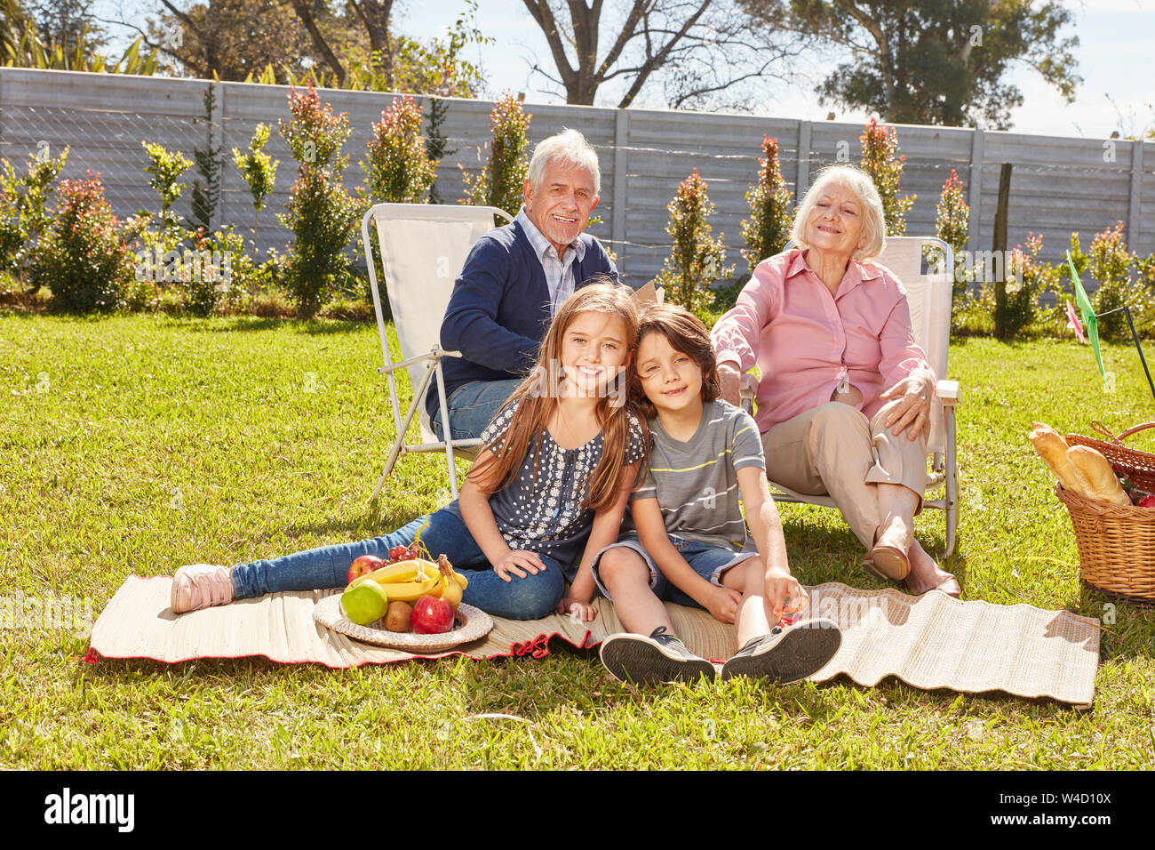 Nipoti e nonni siedono insieme al picnic estivo in giardino Foto Stock