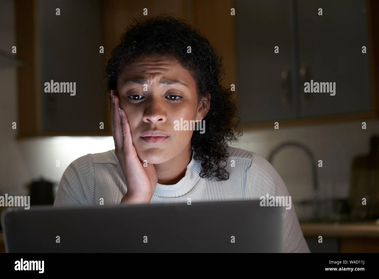 Donna infelice a casa con il computer di essere vittima di bullismo online sui Social Media Foto Stock