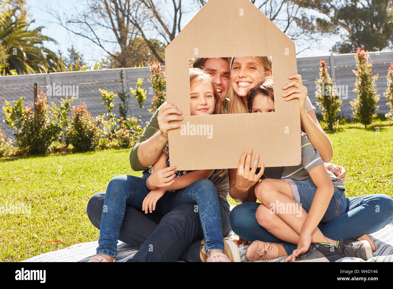Famiglia con due bambini è in possesso di ombrello sopra la testa come un simbolo della costruzione di casa e assicurazione Foto Stock