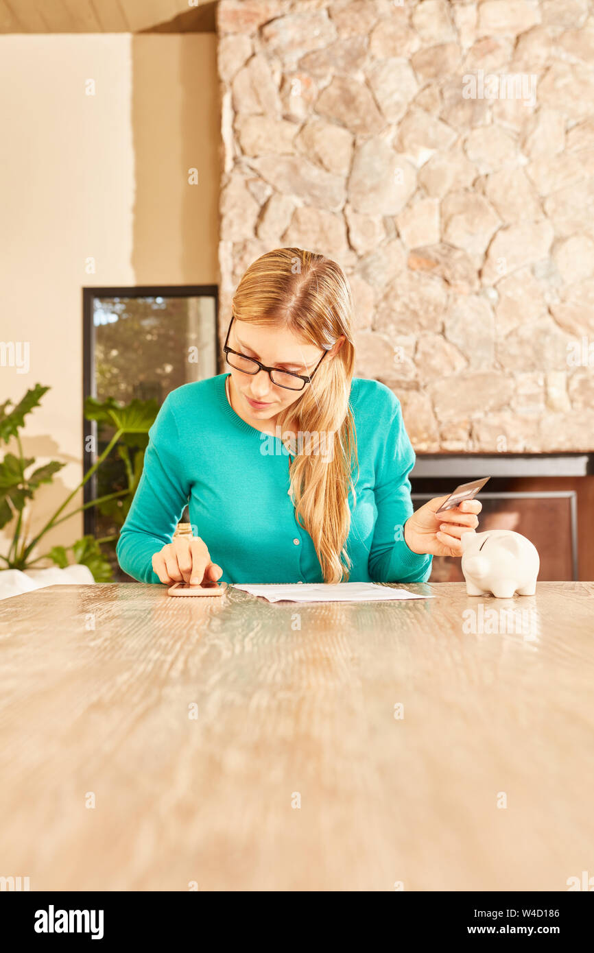 Donna con smartphone come una calcolatrice fa il suo ritorno fiscale a casa Foto Stock