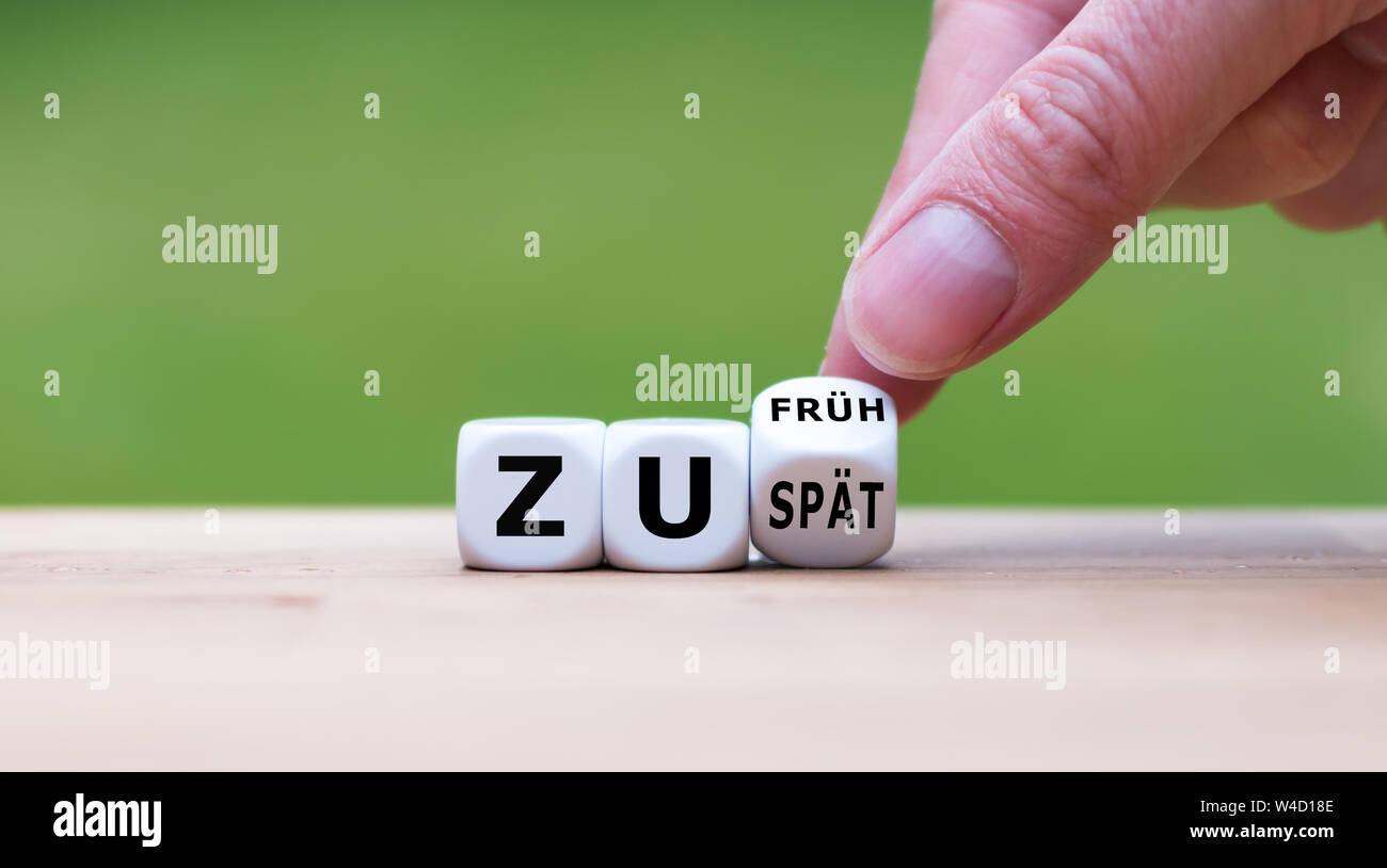 Mano capovolge un dado e cambia l'espressione tedesca "zu spaet' ('troppo tardi" in inglese) a 'zu frueh' ('troppo presto" in inglese) o viceversa. Foto Stock
