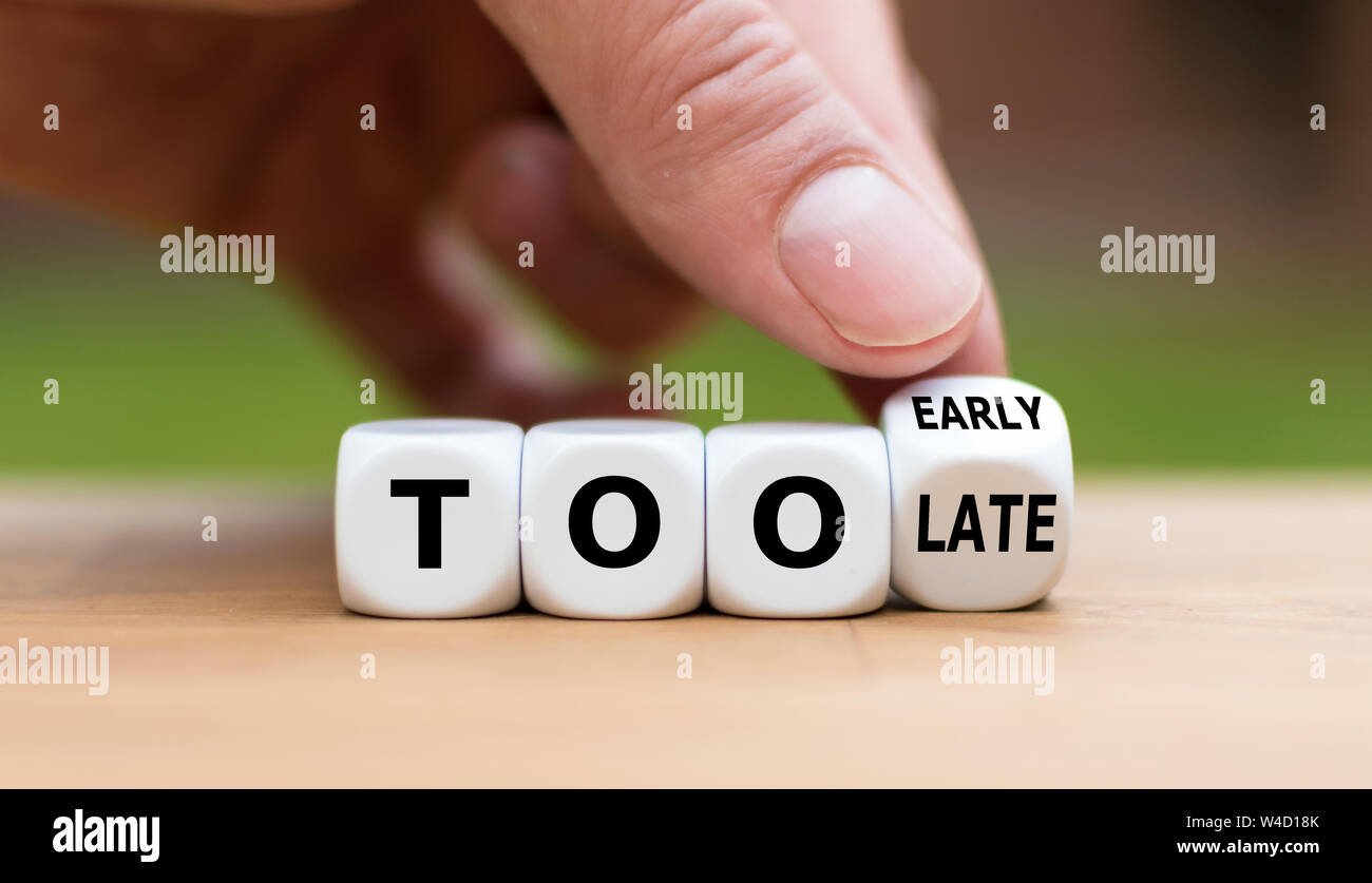Mano capovolge un dado e cambia l'espressione "troppo tardi" a "troppo presto' o viceversa. Foto Stock