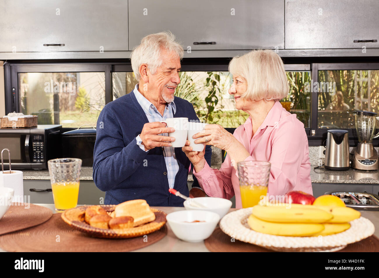 Felice coppia senior è di avere una tazza di caffè mentre si consuma la colazione nella cucina Foto Stock
