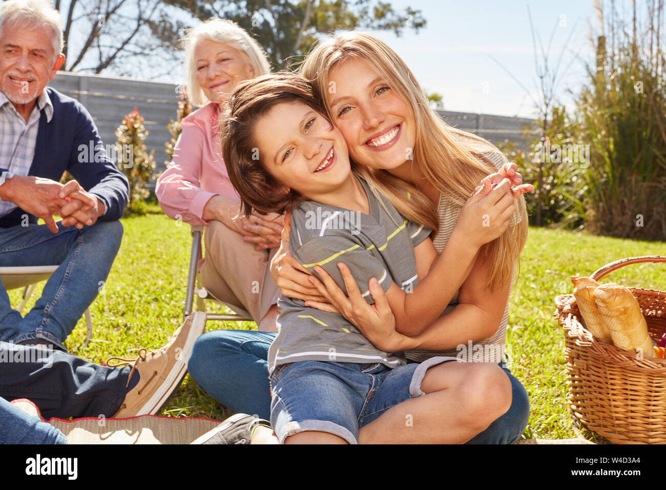 La madre abbraccia il suo figlio a un picnic con i nonni in giardino Foto Stock