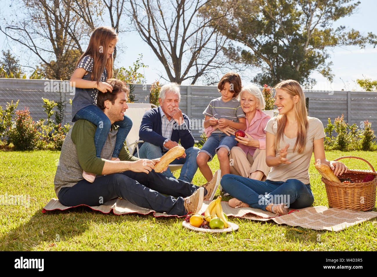 Famiglia di tre generazioni celebra una festa estiva con picnic nel giardino Foto Stock