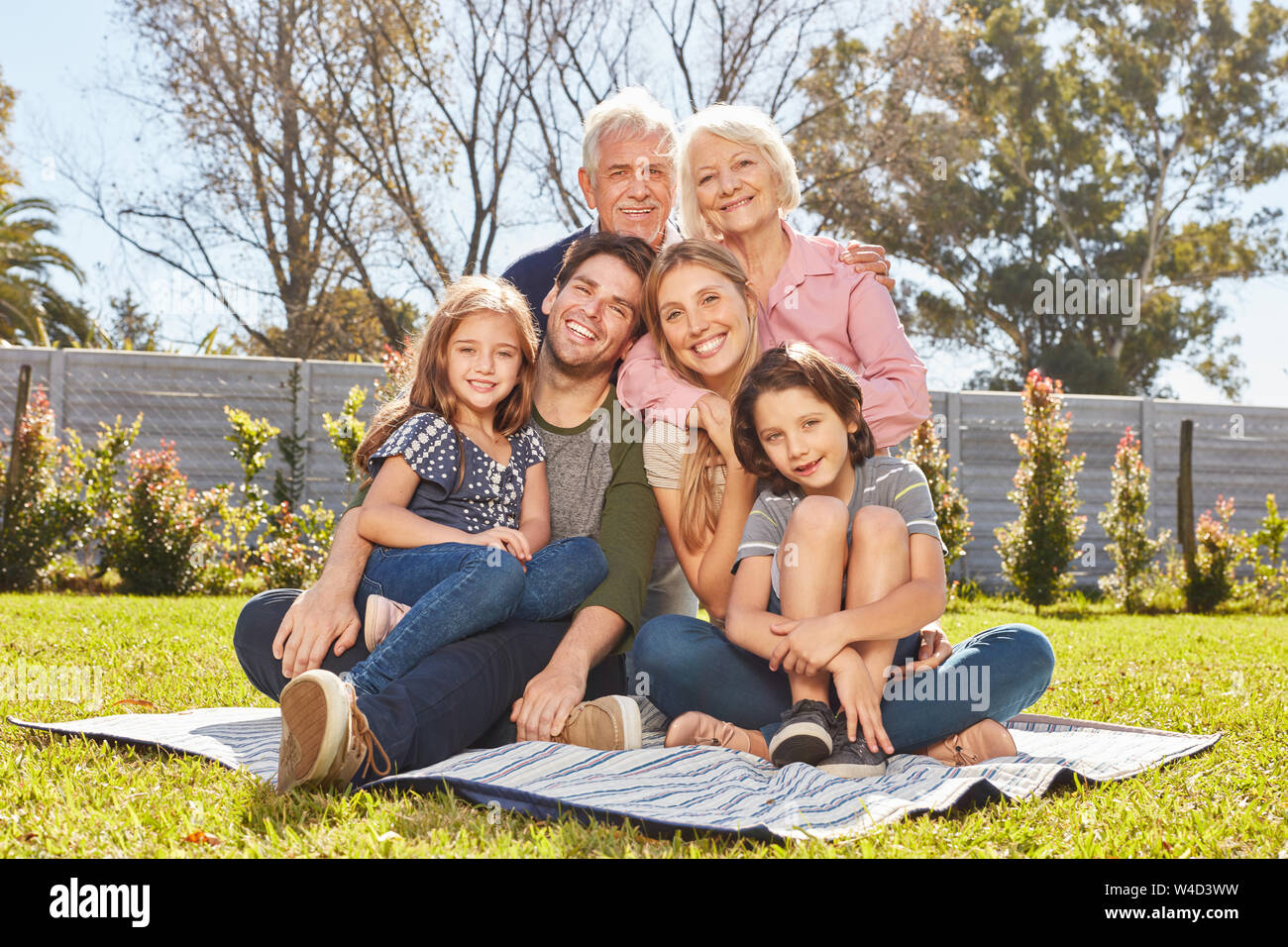 Felice famiglia estesa con due bambini e nonni in estate nel giardino Foto Stock
