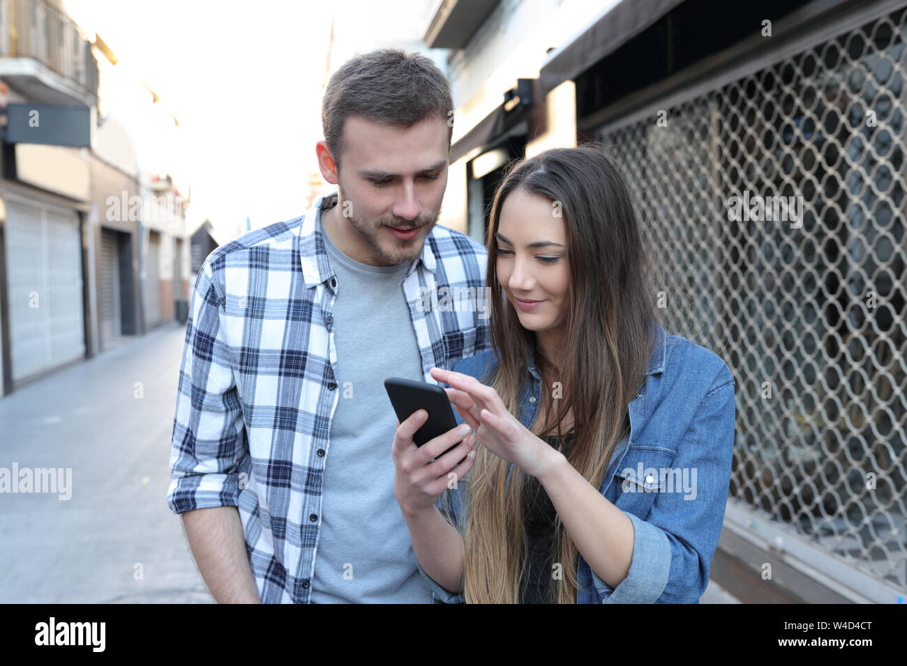 Paio di camminare e di controllo smart phone insieme il contenuto in strada Foto Stock