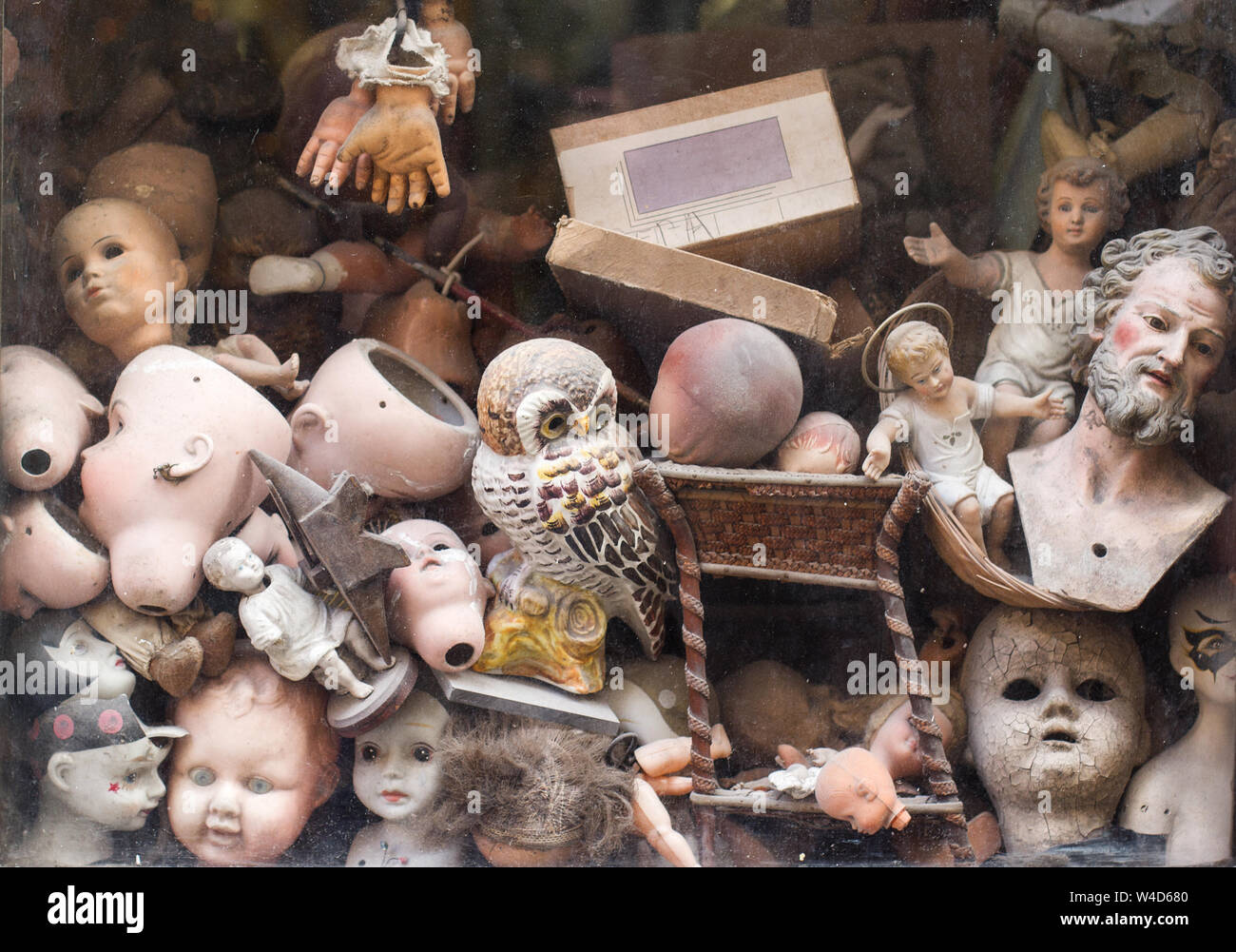 Orizzontale vista anteriore closeup vintage di officina di riparazione finestra con varie rotte fantoccio testa di bambola parti con facce horror Foto Stock