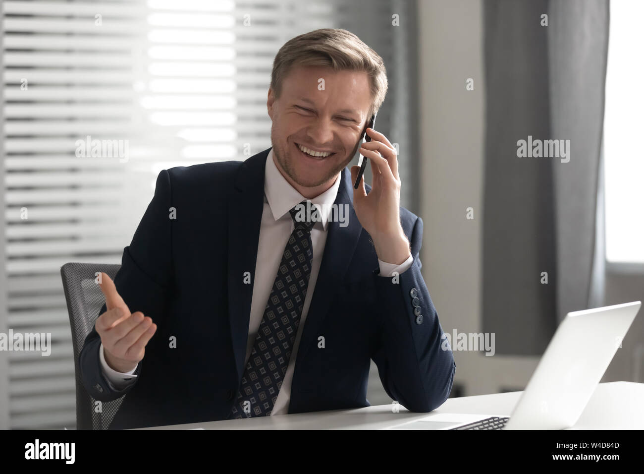 Happy businessman indossare tuta ridere parlando al telefono in ufficio Foto Stock