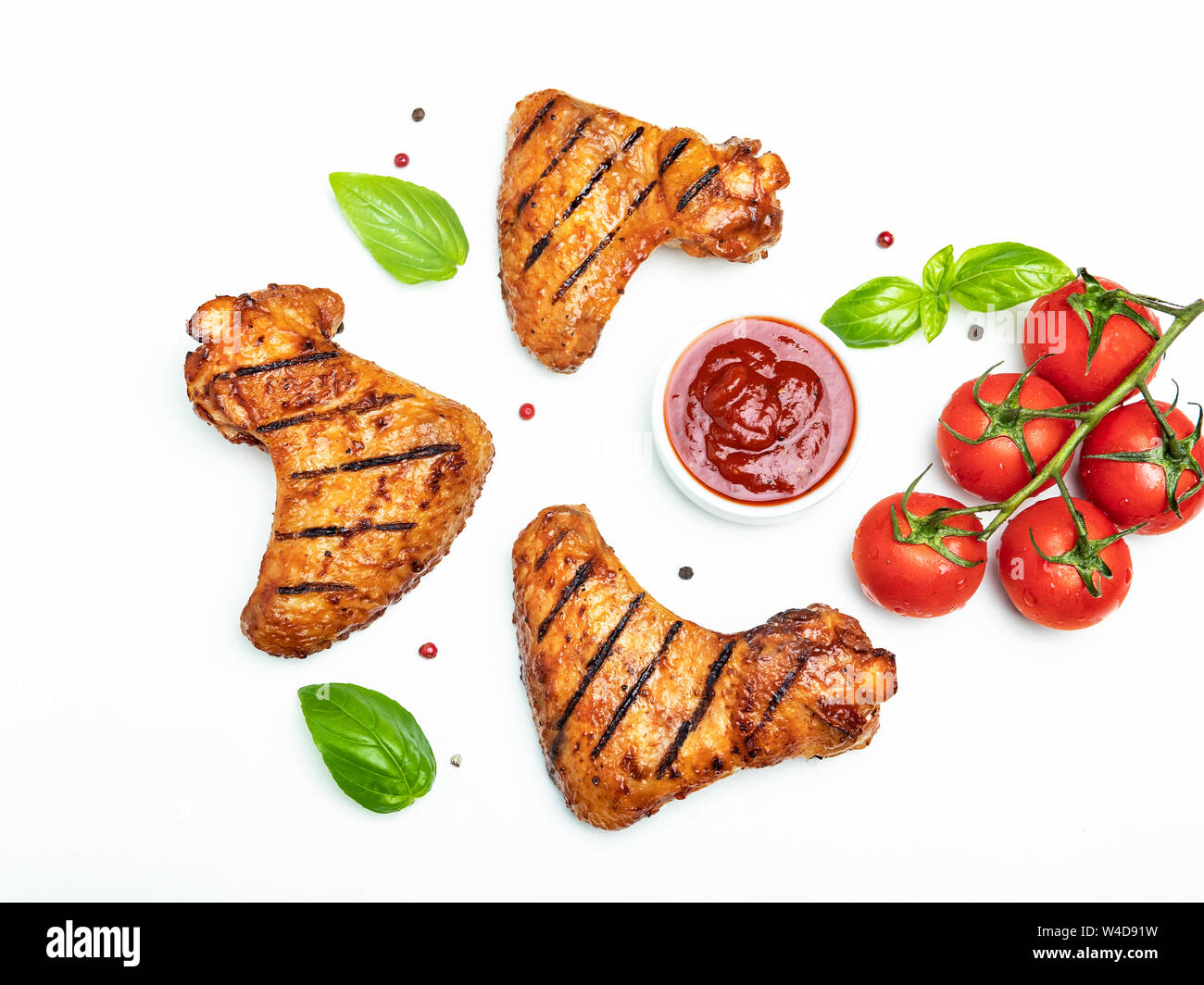 Grigliata di ali di pollo, rosso bbq sauce pomodori basilico spezie su sfondo bianco Foto Stock
