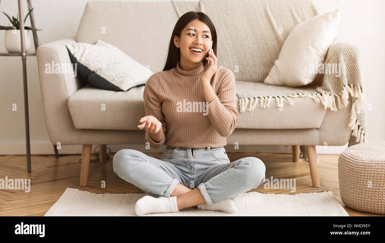 Ragazza asiatica comunicante con un amico, parlando al telefono Foto Stock
