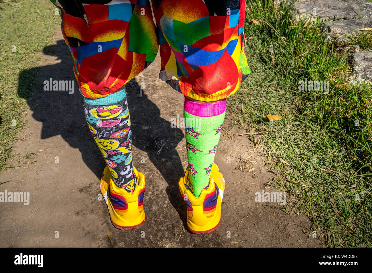 Uomo con abbigliamento multicolore, calzini e scarpe da ginnastica Foto Stock