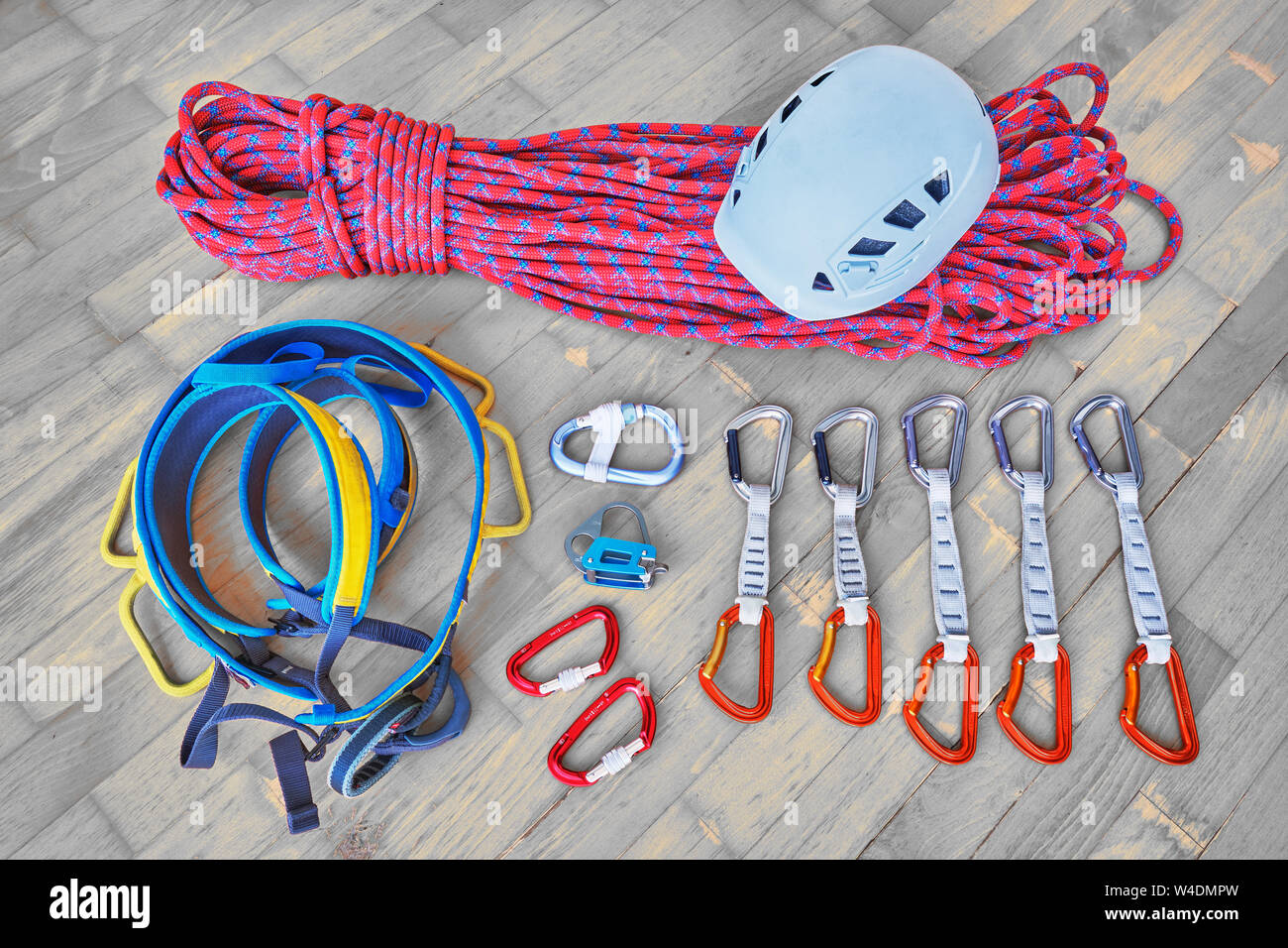 Concetto di imballaggio di arrampicata sportiva marcia per un viaggio. Casco, corda, cablaggio dispositivo di assicurazione, moschettoni, quickdraws su sfondo di legno. Foto Stock