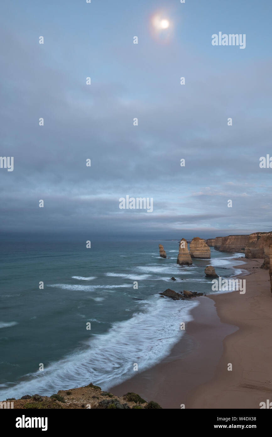 Sfocata a causa della lenta velocità di otturatore, onde si infrangono in Australia dodici apostoli sulla costa ad alba con la luna piena al di sopra Foto Stock