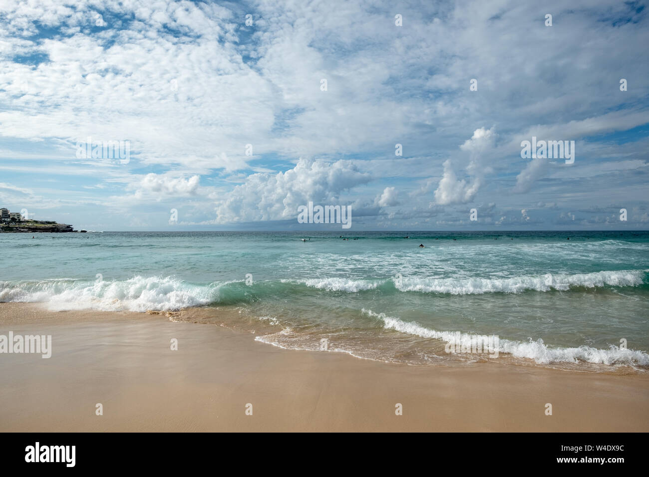 Come il turchese onde si infrangono sulla splendida spiaggia di sabbia dorata a Bondi, Sydney, surfisti sono senza lasciarsi scoraggiare dalle nubi e pioggia sull orizzonte Foto Stock