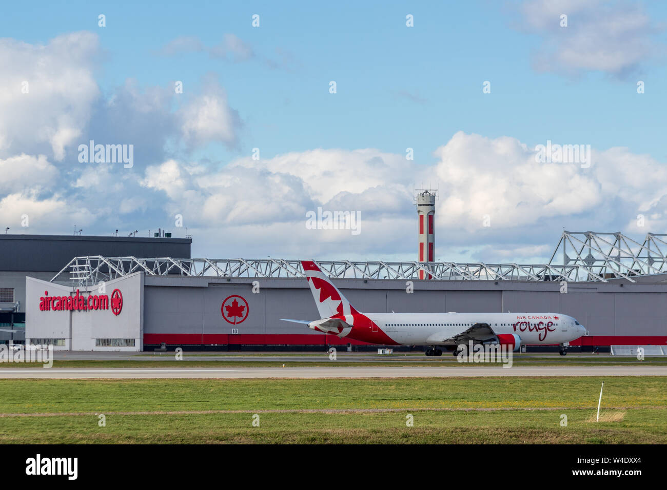 Air Canada Rouge Boeing 767 passa da Air Canada appendiabiti principale all'Aeroporto Internazionale Pierre Elliot Trudeau. Foto Stock